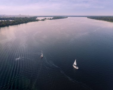 Gün batımında nehirde iki yat açılıyor.