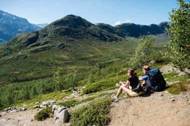 couple of hikers resting on Besseggen ridge in Jotunheimen National Park, Norway clipart