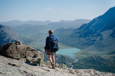 man hiking on Besseggen ridge over Gjende lake in Jotunheimen National Park, Norway  clipart