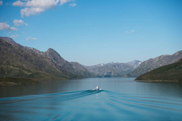 boat floating on calm blue water of Gjende lake, Besseggen ridge, Jotunheimen National Park, Norway 