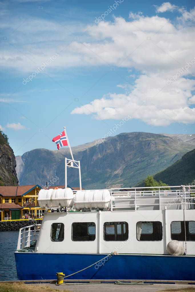 AURLANDSFJORD, FLAM, NORWAY - 27 JULY, 2018: boat with norway flag moored in harbour at Aurlandsfjord, Flam (Aurlandsfjorden), Norway