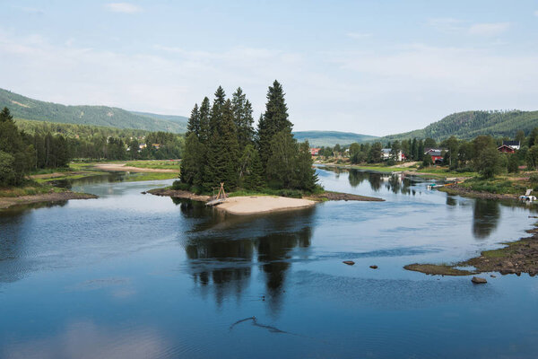 small island with fir trees on river, Trysil, Norway's largest ski resort 