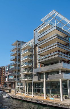 OSLO, NORWAY - 28 JULY, 2018: low angle view of contemporary houses and embankment at Aker Brygge district, Oslo  clipart