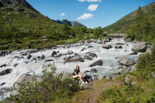Randonneur assis près de la rivière de montagne sur la crête de Besseggen dans le parc national de Jotunheimen, Norvège — Photo de stock