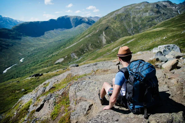 Viajero con mochila descansando en Besseggen ridge en Jotunheimen National Park, Noruega - foto de stock