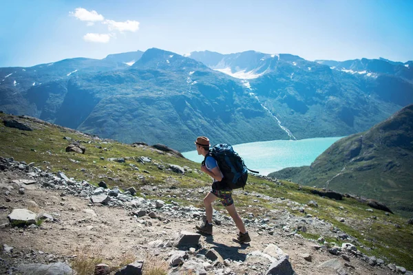 Hiker with backpack walking on Besseggen ridge over Gjende lake in Jotunheimen National Park, Norway — Stock Photo