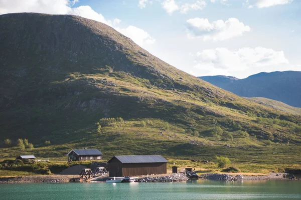Casas y barco amarrado en el lago Gjende, cresta Besseggen, Parque Nacional Jotunheimen, Noruega - foto de stock