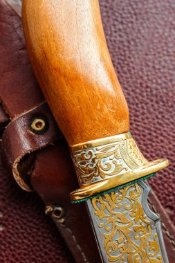 Koyu kahverengi deri arka planda av bıçağı.