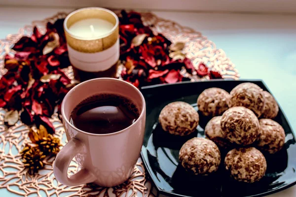 Cup of tea sweets candle and rose petals on the table. — Stock Photo, Image