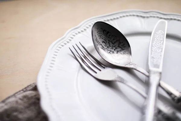 Cutlery on the white plate. Silver fork knife and spoon. Wooden table. — Stock Image Cutlery on the white plate. Silver fork knife and spoon. Wooden table. Royalty Free Stock Images
