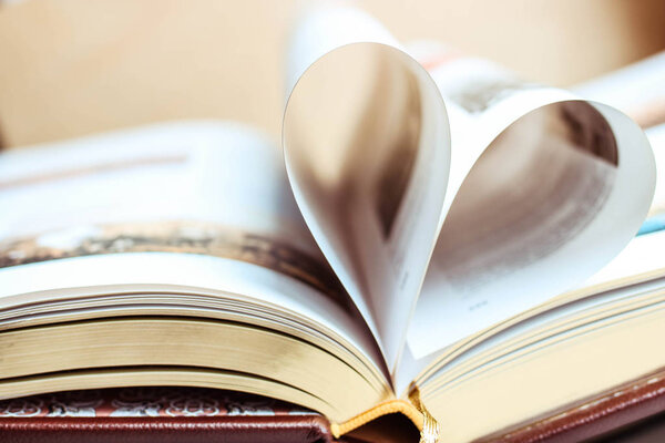 Big book with golden pages in the image of the hert. Love reading books concept.