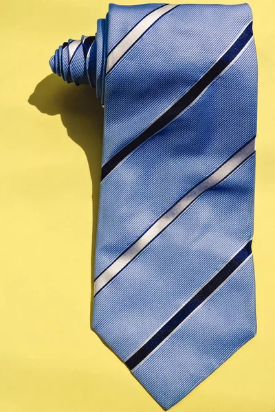 Голубой полосатый галстук на желтом фоне вид сверху, творческая фотография . — стоковое фото