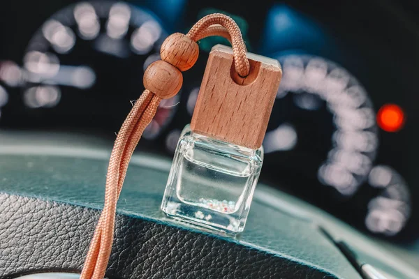 Car perfume or air freshener on the steering wheel and blurred dashboard lights in the background.