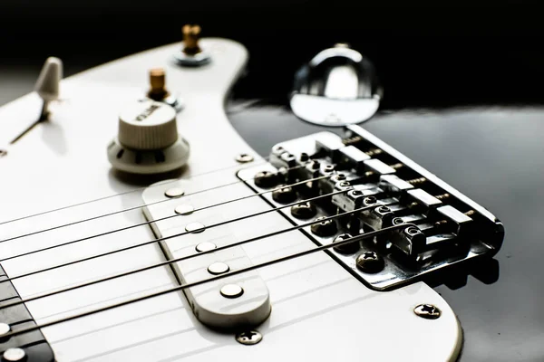 Elektronické černobílé těleso kytary je v blízkosti řetězcích, hlasitosti a tónové kontroly. Pozadí hudby. — Stock fotografie