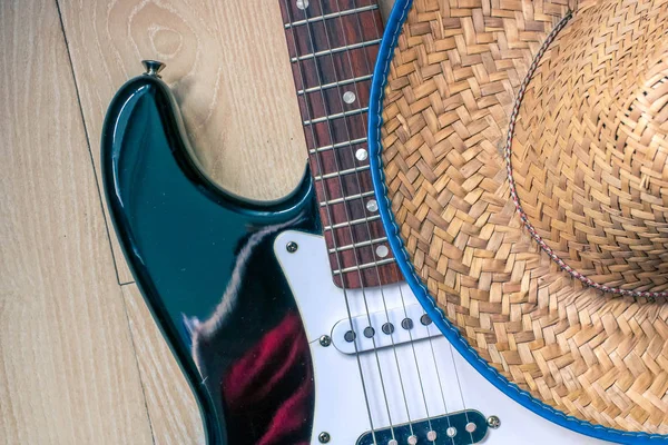 Ahşap masa üzerinde elektronik gitar ve kovboy şapkası yakından görünümü. Country müzik konsepti.