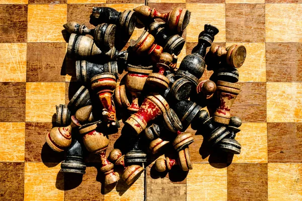 Oude shabby schaakstukken verspreid op een schaakbord. — Stockfoto
