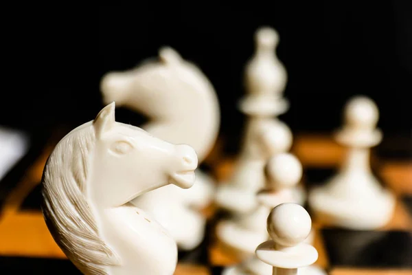 Figuras blancas de ajedrez se cierran sobre fondo negro. Imagen con profundidad de campo poco profunda . —  Fotos de Stock