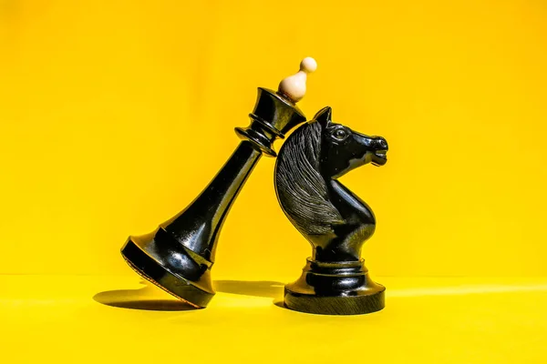 Concepto colorido con rey de ajedrez negro y caballero de ajedrez. Fondo amarillo brillante . —  Fotos de Stock