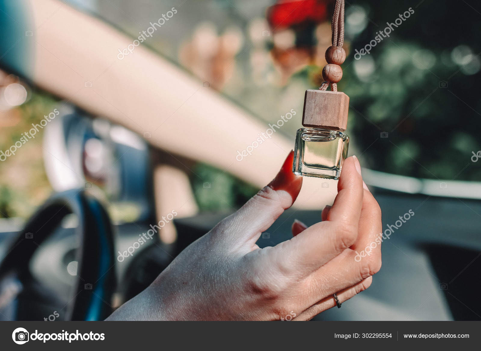 Small glass bottle with car perfume in female hand. Small glass