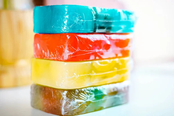 Stos czterech kolorowych kawałków mydła na białym stole z selektywnym naciskiem. — Zdjęcie stockowe