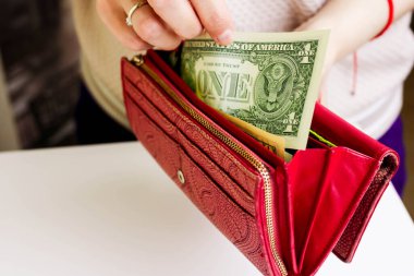 Kadın el, dolar banknotunu beyaz bir masanın üzerinden kırmızı bir çantadan alır. Para kavramı tükendi..