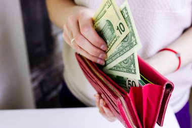 Kadın kırmızı çantasına Amerikan doları koyuyor. Para kavramı kaydet.