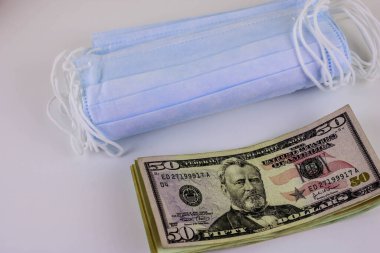 Korunmada daha yüksek fiyatların sembolü olarak bir paket tıbbi maske ve bir deste Amerikan doları.