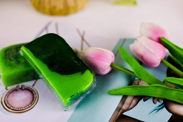 两片浅绿色的手工肥皂盘根错节地站在白桌上 上面插着鲜花 — 图库照片