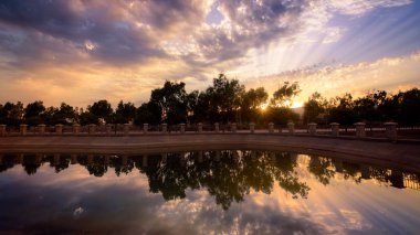 Bir parkta yer alan bir gölde yansıyan günbatımı