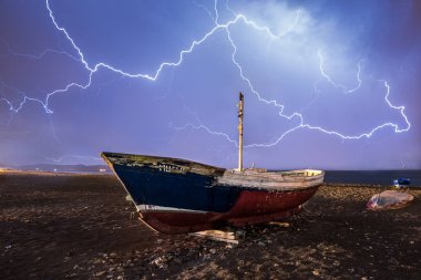 Almeria denize düşen bir yaz gecesi elektrik fırtınası. Terk edilmiş tekneler ile plaj.