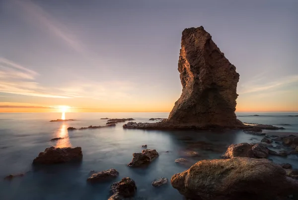 Dawn on this beach between Carboneras and Mojacar, two towns in the province of Almeria (Spain), the rock that stands out seems to resemble a hat perched in the water.