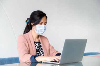 Ofisinde dizüstü bilgisayarı olan Asyalı genç kadın.