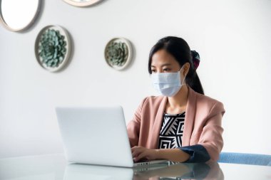 Ofisinde dizüstü bilgisayarı olan Asyalı genç kadın.