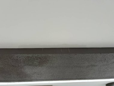 Tavandaki sızıntıdan kaynaklanan kara su lekesi duvarda soyut bir doku oluşturuyor. Ev sigortası ve yenileme ve onarım için ciddi ev sorunları
