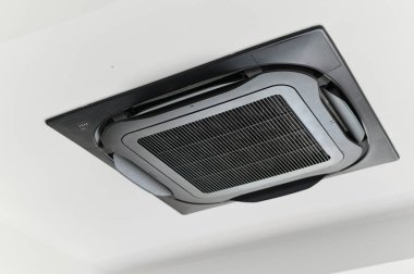 Verimli iklim kontrolü için modern siyah tavan kaset klima ünitesi. Soğutma sistemi temiz hava solunumu sağlıyor ve rahat bir atmosfer yaratıyor.