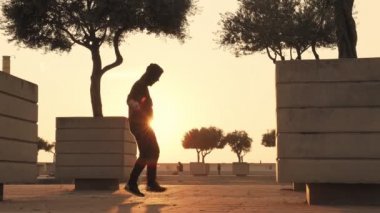 Güçlü adam parkta bir ipin üzerine atlar. oung adam güneşli bir günde spor için gider. Adam çeşitli egzersizler ile vücut kasları trenler. Atletik adam hızlı bir ip üzerinde atlar inşa