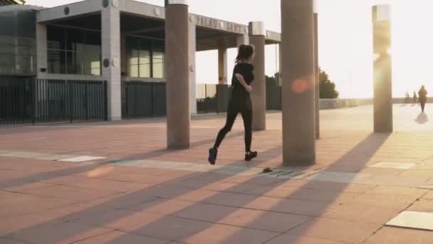 The girl runs past the columns in the Park. Obstacle course. Training in the fresh air. Woman running through the area. A young woman engaged in cardio.Healthy lifestyle. Body training. Fitness load — Stock Video