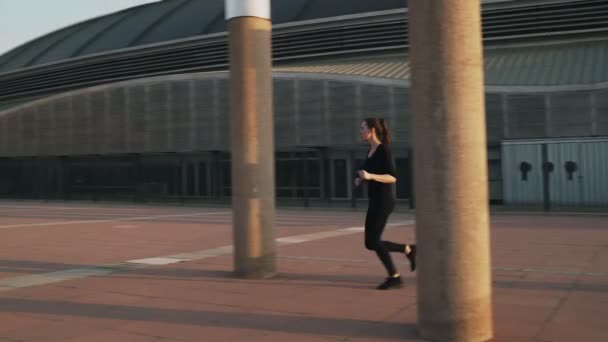 The girl runs past the columns in the Park. Obstacle course. Training in the fresh air. Woman running through the area. A young woman engaged in cardio.Healthy lifestyle. Body training. — Stock Video