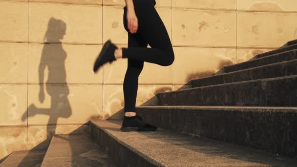 Het meisje strekt de spieren van de voeten voor de training. Een jong meisje uitgerekt beenspieren voor een running workout in de zon — Stockvideo