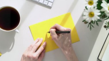 Ofisteki genç bir kadın sarı bir zarf imzalar ve kalp şeklinde damga vurur. Kadın masasındaki arkadaşlarına mektup gönderiyor. Orada beyaz bahar çiçekleri ve sabah kahvesi var..