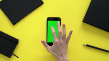 Telefonundaki bandı karıştıran genç bir kadın. Akıllı telefonunda parmak izi mesajı var. Kadın sarı bir ofiste oturuyor. Etrafı ofis defterleri, klasörler ve telefonundaki bantlarla çevrili..