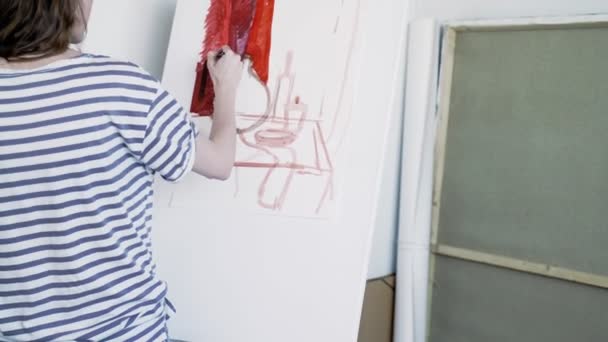アーティストはキャンバスに描きます。白いキャンバスに描かれた赤い線は、プレートボトルの形を形成します。芸術家は静物を描き、背景を赤で塗る. — ストック動画