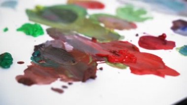 Boyama için akrilik boya paletüzerine bulaşmış. Sanatçı gerekli renk tonlarını arıyor. Sanatçı tuvale uygulamadan önce akrilik boyaları karıştırır