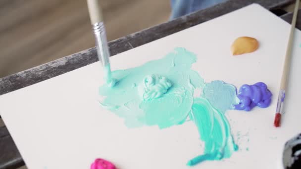 L'artiste ajoute de la peinture à la palette. Peinture goutte à goutte morceaux sur la palette artistique. La peinture acrylique bleu doux est pressée hors du tube sur la palette. L'artiste enduit une peinture pelucheuse au pinceau — Video