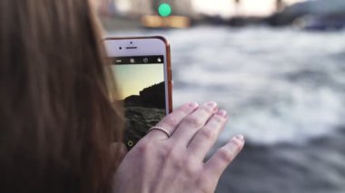 Genç ve güzel bir kız tekne gezisi sırasında telefonla fotoğraf çekiyor. Saint Petersburg, Leningradskaya Oblastı / Rusya - 22.08.2019: Saint Petersburg, Rusya 'nın nehir ve kanallarına tekne gezisi. Küçük dalgalar, parklar, saraylar.