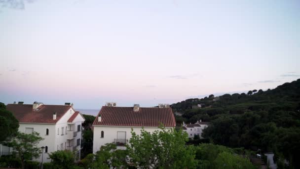 Bellissimo tramonto in una piccola cittadina costiera mediterranea. Cielo viola e rosa e mare viola. Case bianche sulla costa. Pace e tranquillità. Nuvole rosa nel cielo del tramonto. Vacanze al mare — Video Stock