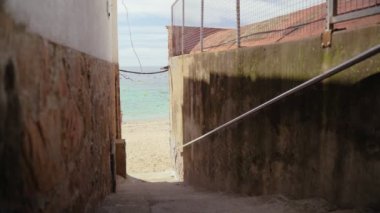 Küçük bir Akdeniz kasabasında dar bir sokaktan güzel bir deniz manzarası. Köy, göz kamaştırıcı zümrüt körfezinin kıyısında. Deniz kenarında güneşli bir yaz günü. Sahilde tatiller. Picturesque Caddesi..