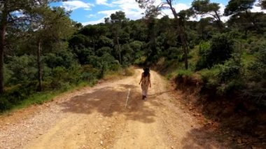 Yürüyüş. Sırt çantalı bir kız orman yolunda yürüyor. Ormanda yürüyüş. Yeşil ormandaki altın ışık. Orman yürüyüşü. Güneşli bir yaz günü. Ağaçların arasında yürüyorum. Kırsal kesimde tatiller.