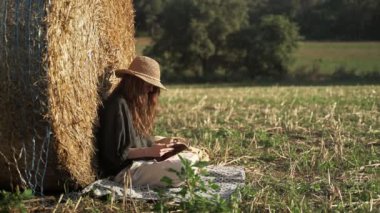 Genç bir kadın sahada serinliyor. Siyah gömlekli ve hasır şapkalı bir kız samanlığa yaslanıp günlüğünü karıştırıyor. Köyde bir tatil. Güneşli bir yaz günü. Kırsal kesimde tatil