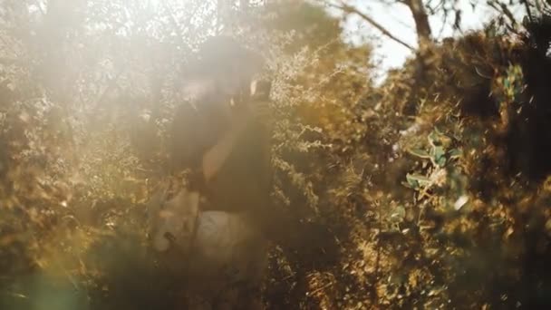 En ung kvinna fotograferar träd på en smartphone i skogen. En tjej i svart skjorta och en halmhatt filmar skogen. Semester i byn. Solig sommardag. Vind blåser långt hår. — Stockvideo